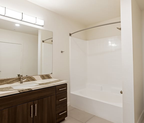 A modern bathroom with a white tub and a large mirror. at Elements Apartments, Irvine, CA