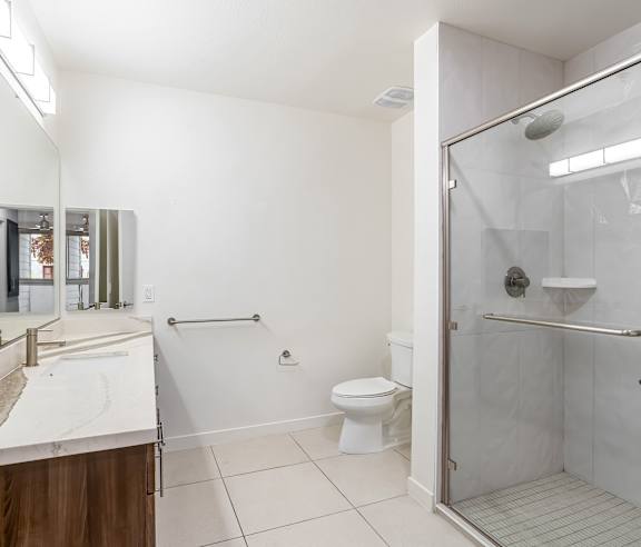 A white bathroom with a walk in shower and a toilet. at Elements Apartments, Irvine, CA