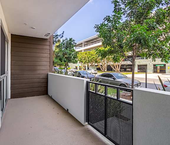 A balcony with a black railing and a grey wall. at Elements Apartments, Irvine, CA
