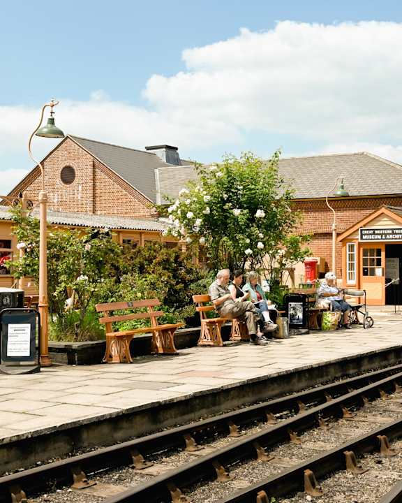 A group of people are sitting on a bench at a train station.