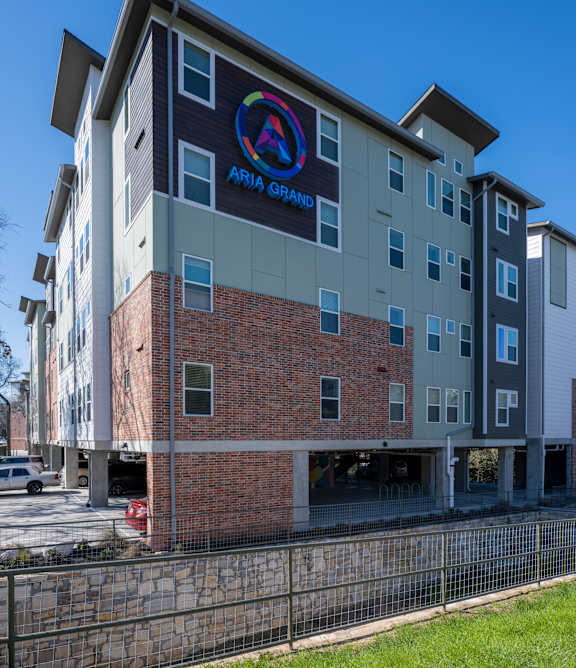 A modern apartment complex with a well-maintained lawn in front.