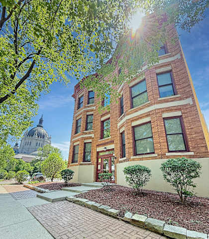 A building with a brick facade and a dome in the background.