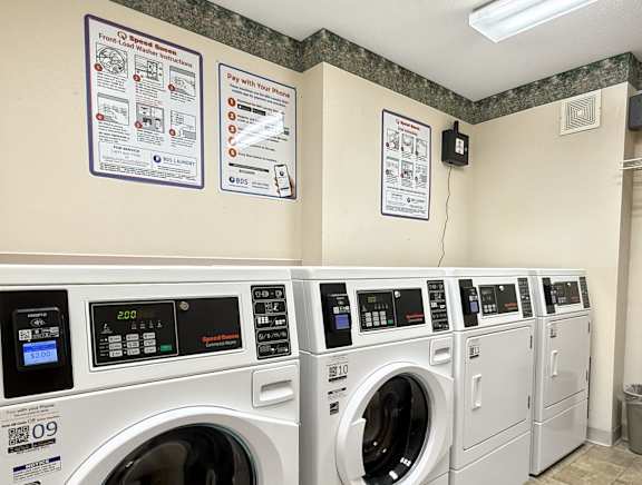 A row of front loading washing machines in a public laundromat.