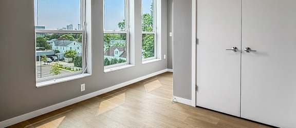 A room with a white door and a window overlooking a cityscape.