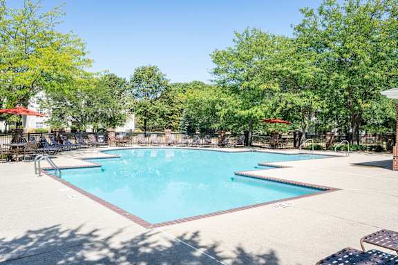 A large swimming pool surrounded by lounge chairs and umbrellas.