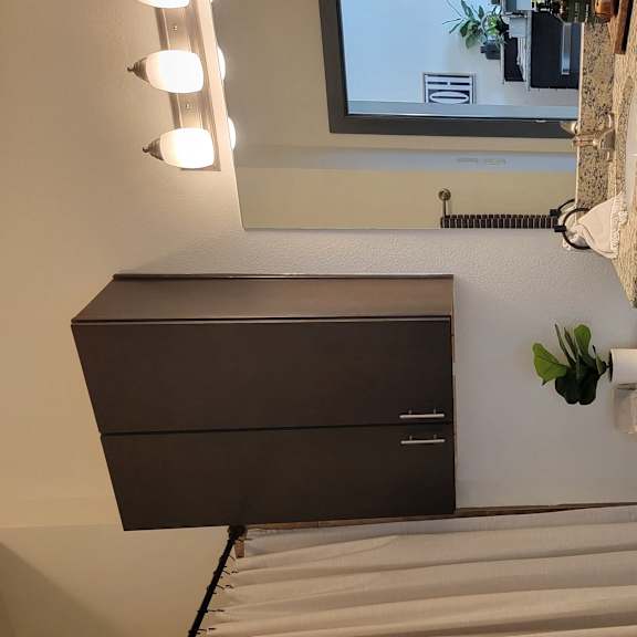 A bathroom with a sink, mirror, and cabinet.