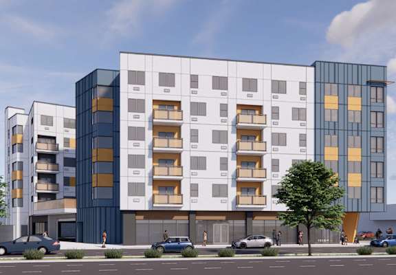 A modern multi-story building with balconies and a parking lot in front.