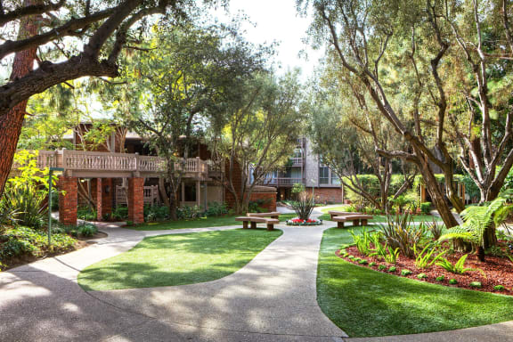 a courtyard with benches and trees in front of a building