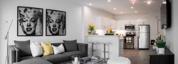 a living area with a couch coffee table and a kitchen in the background