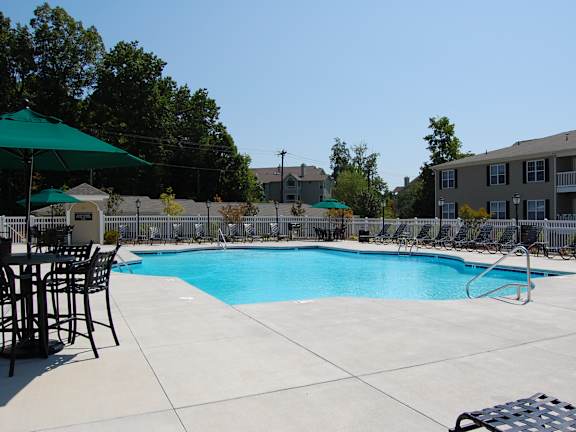 A large outdoor swimming pool surrounded by a fence and chairs.