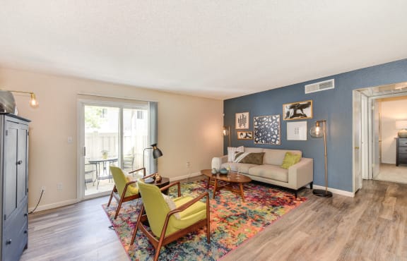 Living Room with Hardwood Inspired Floor, Lime Sofa Chairs, Gray Sofa, Colorful Rug and Sliding Door to Patio