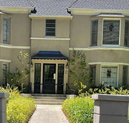 a house with a blue awning and wreaths hanging in the windows