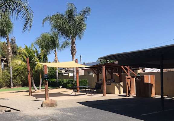 a parking lot with a building in the background and palm trees in the foreground