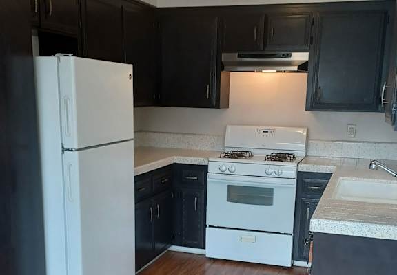 a kitchen with black cabinets and white appliances