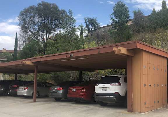 a carport with awning and cars parked under it