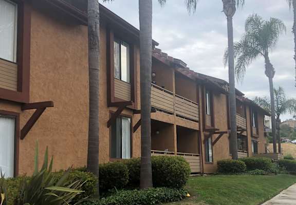 a row of apartment buildings with palm trees in the background
