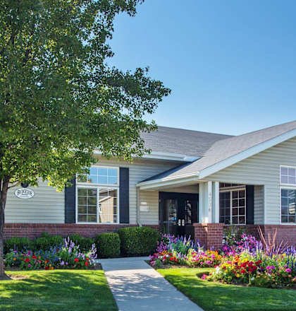the front of a house with a sidewalk and a tree