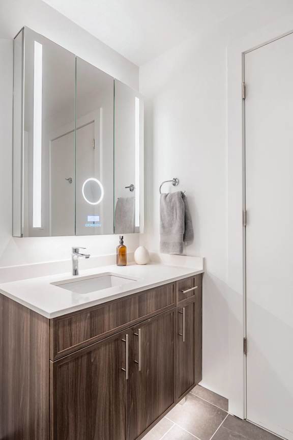 A bathroom with a white sink and brown cabinets.at Essen Apartments, Alexandria, VA