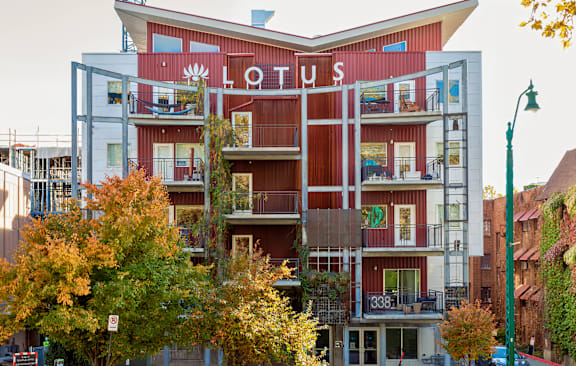 A red and white building with balconies and a tree in front.