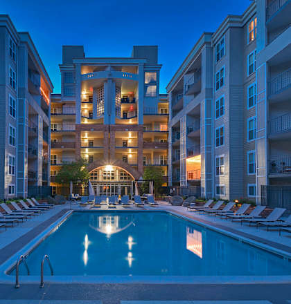 a swimming pool at night in front of an apartment building at The Citizen at Shirlington Village in Arlington, Virginia
