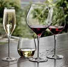 Four glasses of wine are lined up on a table.