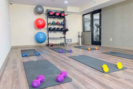 a gym with yoga mats and dumbbells on the floor