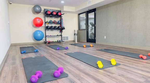 a gym with yoga mats and dumbbells on the floor