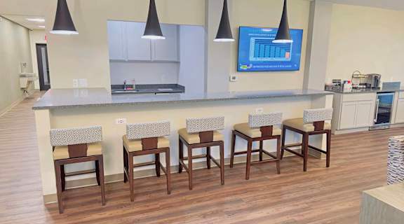 a kitchen with a bar and chairs in front of a counter