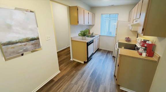 a kitchen with wooden floors and a painting on the wall