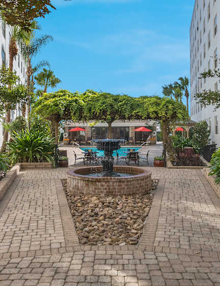 A courtyard with a fountain surrounded by palm trees and buildings.
