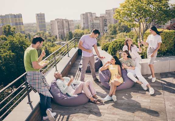 A group of people are sitting and standing on a rooftop terrace.