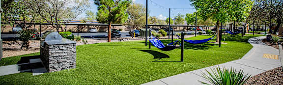 A sunny day at a park with a blue hammock.