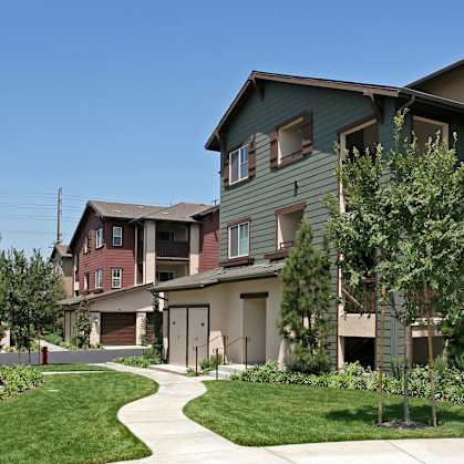 A row of houses with a sidewalk in front.