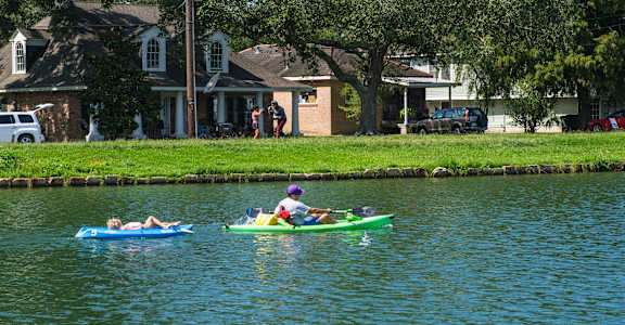 Two people are kayaking on a calm body of water.