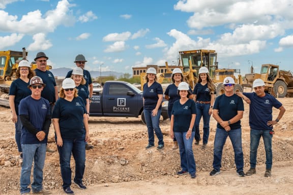 a group of people posing for a photo in front of a construction site with machinery