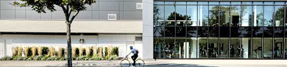 A person riding a bicycle in front of a modern building.