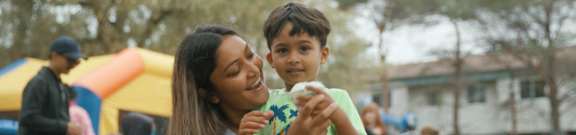 A woman and a boy are eating popcorn at an outdoor event.