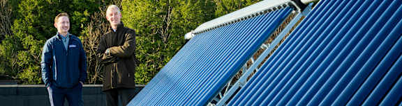 Two men standing in front of a blue corrugated metal structure.