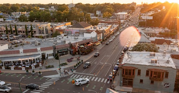A sunset view of a busy intersection with cars and pedestrians.