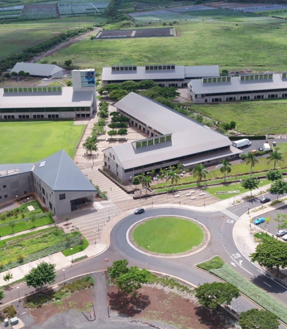 an aerial view of a large building with a green field next to it