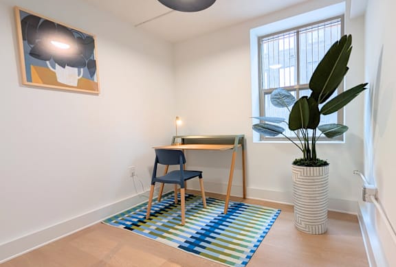 A room with a blue chair and a painting on the wall.