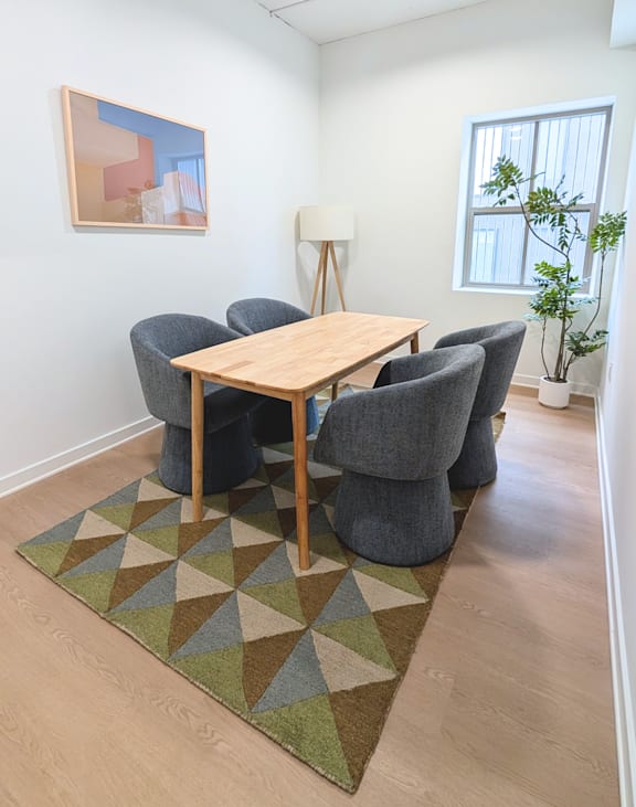 A room with a table and chairs and a plant.