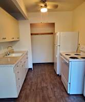 A kitchen with white appliances and wooden floors.