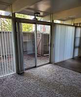 A room with a carpeted floor and sliding glass doors.