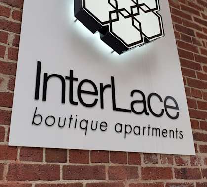 A sign for InterLace boutique apartments is displayed on a brick wall.