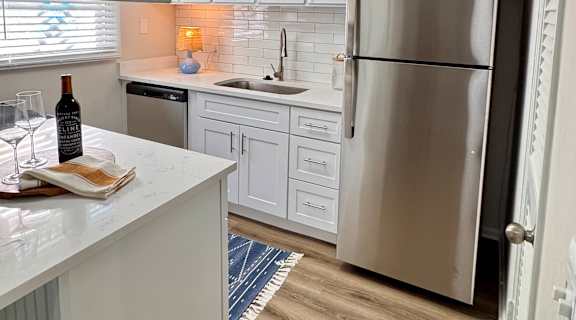 A kitchen with white cabinets and a stainless steel refrigerator.