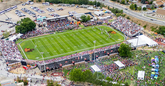 A large stadium with a green field and a crowd of people watching a game.