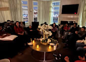 Thumbnail 17 of 17 - A group of people are sitting around a table in a room.