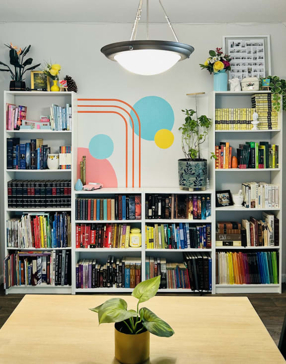 a bookshelf filled with books and a table with a plant
