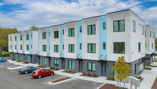 a row of apartment buildings with cars parked in front of them